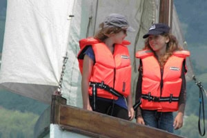 Zwei Mädchen mit Schwimmweste stehen auf einem Kutter