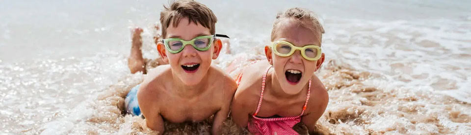 Zwei Kinder liegen in der Brandung und haben Spaß