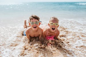 Zwei Kinder liegen glücklich in der Brandung des Meeres