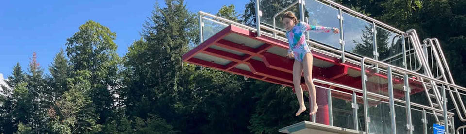 Mädchen springt vom Sprungturm im Freibad
