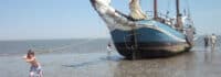Junge zieht Segelschiff übers Watt