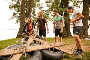 Kinder bauen gemeinsam ein Floß im Wildniscamp am Schweriner See