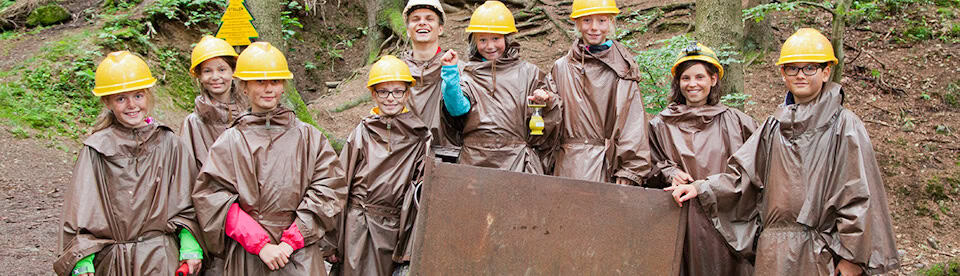Kinder stehen mit Helm vor einer Lore