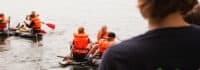 Kinder fahren mit ihren selbstgebauten Floßen auf dem Wasser