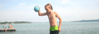 Junge mit Ball am Wasser