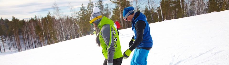 Zwei Jugendliche lernen Snowboard fahren