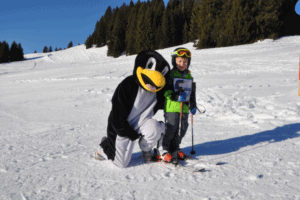 Kind mit Pinguin auf Skiern