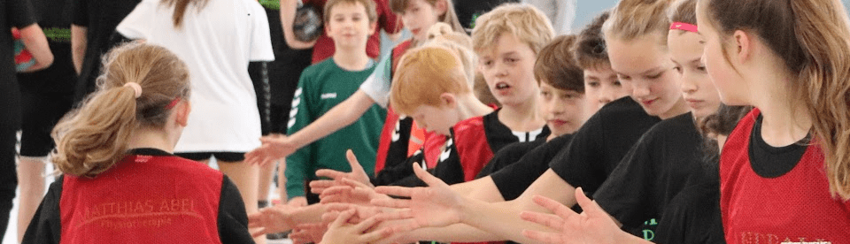 Sportcamp mit Handball, Kinder klatchen sich ab