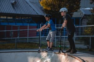 Zwei Kinder mit Scooter auf Rampe im Scooter Camp