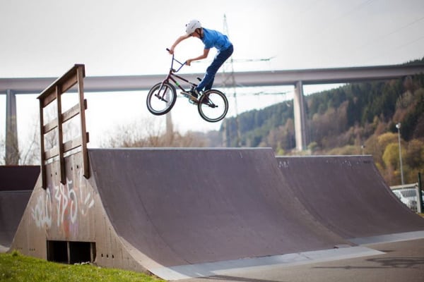 Junge springt mit BMX auf Rampe