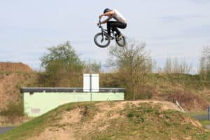 BMX-Fahrer springt über Hügel im BMX und Scooter Camp