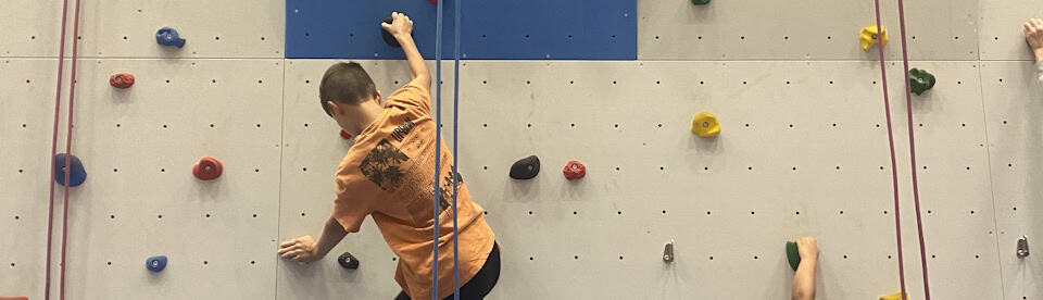 Ein Junge klettert an der Kletterwand