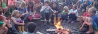 Kinder und Jugendliche sitzen am Lagerfeuer