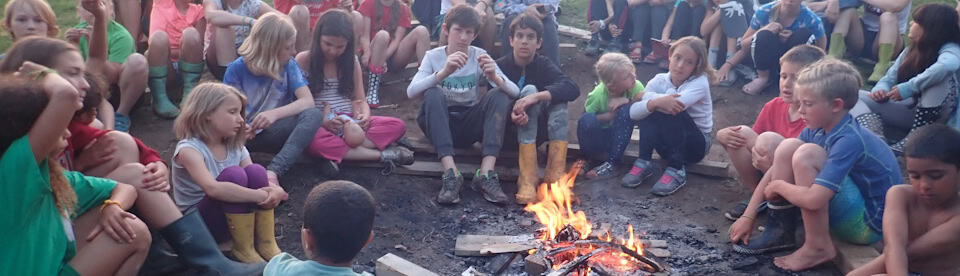 Kinder und Jugendliche sitzen am Lagerfeuer