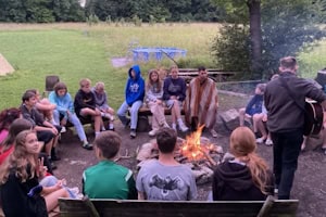 Jugendliche sitzen am Lagerfeuer