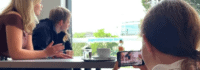 Drei Mädchen filmen eine Szene am Tisch