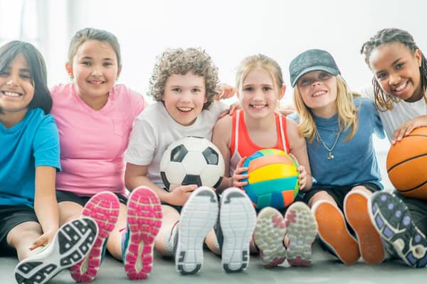 Kindern sitzen nebeneinander mit bunten Bällen in den Händen