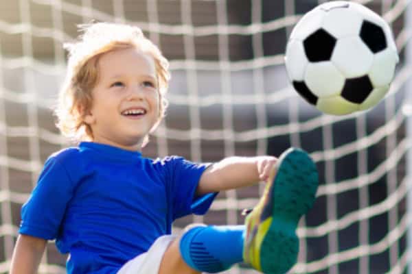 Junge spielt mit dem Ball vor dem Netz