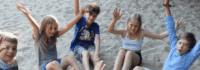Kinder sitzen glücklich im Sand