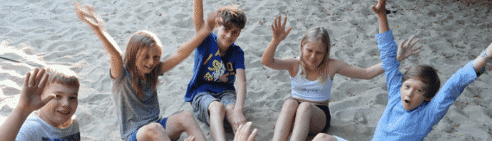 Kinder sitzen glücklich im Sand