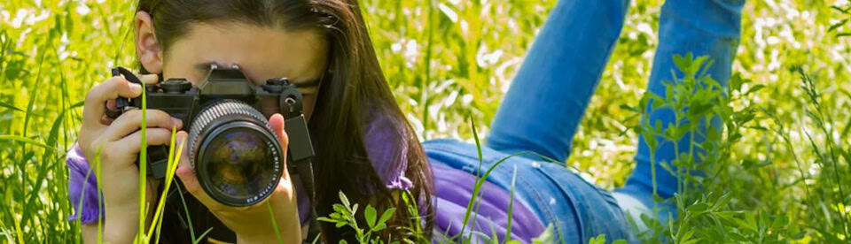 Mädchen filmt auf einer Wiese