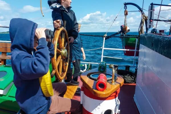 Junge am Steuerboard beim Englisch auf dem Segelschiff Pippilotta