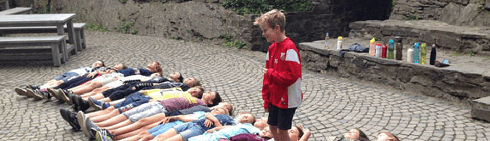 Kinder liegen auf dem Boden und eine Junge steht