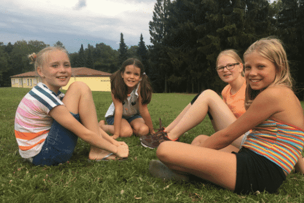 Vier Mädchen sitzen lachend auf dem Rasen