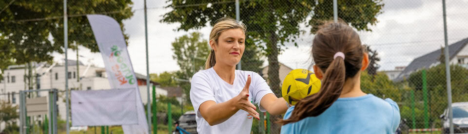 Ein Mädchen und eine Betreuerin werfen sich einen Ball zu