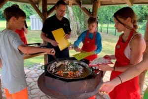 Kinder stehen um eine Grillschale und kochen zusammen