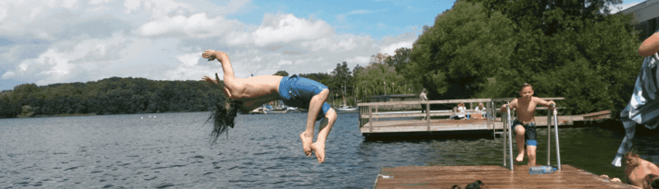 Ein Junge springt in den See