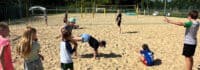 Kinder spielen Gruppenspiele auf Beachvolleyball-Feld