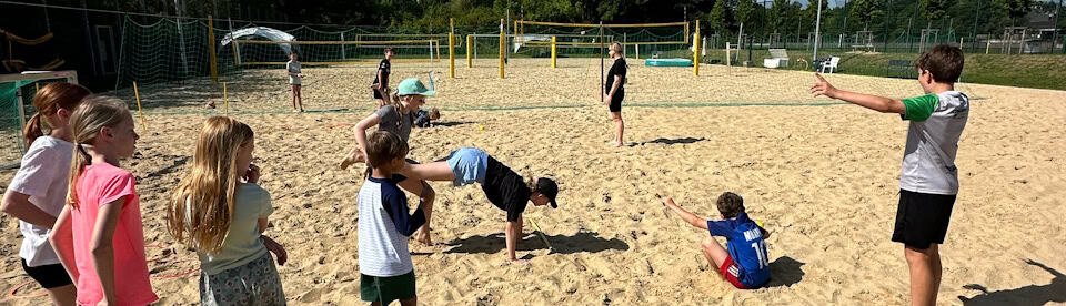 Kinder spielen Gruppenspiele auf Beachvolleyball-Feld