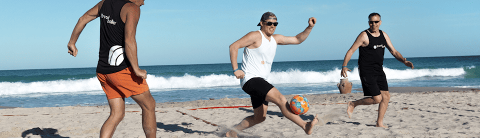 3 Männer spielen Beachsoccer