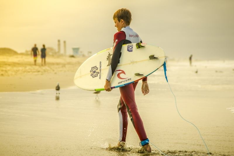 Surferjunge am Strand im Feriencamp