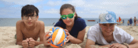 drei Jugendliche mit Volleyball im Sand