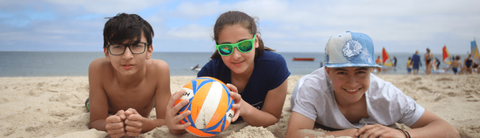 drei Jugendliche mit Volleyball im Sand