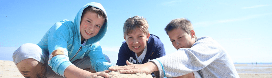 Drei Jungs sitzen im Sand