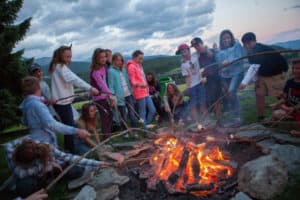 Gruppe steht um Lagerfeuer im Activity Camp Salzburger Land