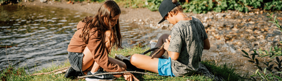 zwei Kinder sitzen am Fluss