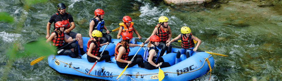 Gruppe sitzt in Schlauchboot bei Rafting Tour